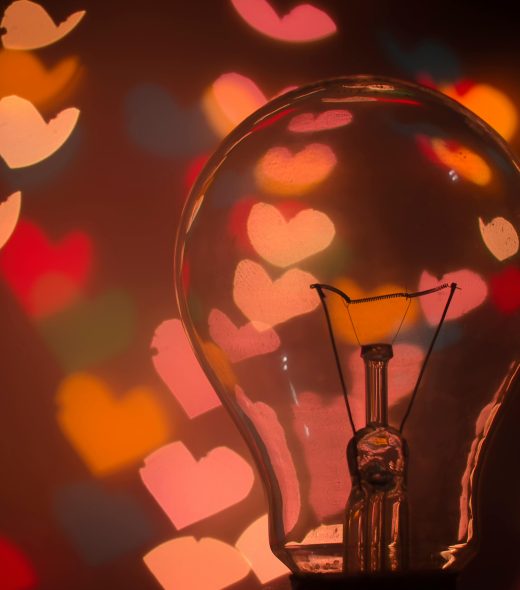 Light bulb with colorful heart-shaped bokeh creating a warm and romantic mood.