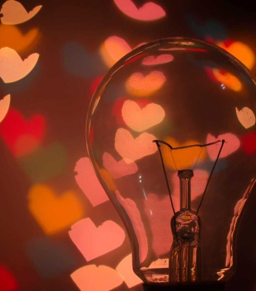 Light bulb with colorful heart-shaped bokeh creating a warm and romantic mood.