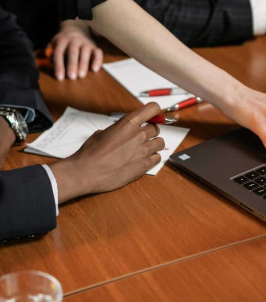 Professionals collaborating over a laptop in a business meeting setting indoors.