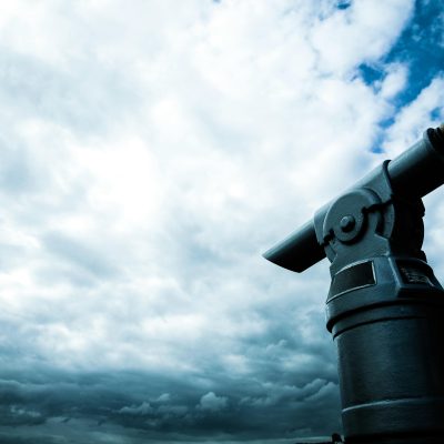 A close-up view of a coin-operated telescope pointing towards a dramatic cloudy sky, capturing a sense of adventure.