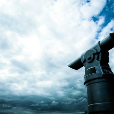 A close-up view of a coin-operated telescope pointing towards a dramatic cloudy sky, capturing a sense of adventure.