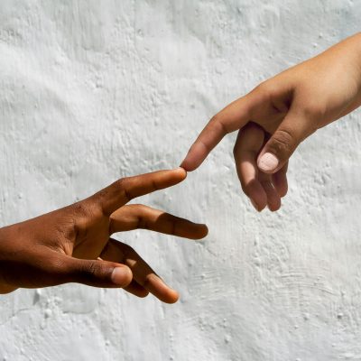 Artistic depiction of human connection with two hands reaching against white backdrop.