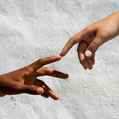 Artistic depiction of human connection with two hands reaching against white backdrop.
